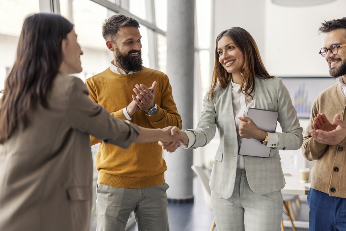 Colleagues applauding as a professional is congratulated with a handshake